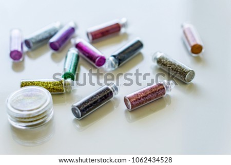 Close-up bottles of colorful glitter for makeup and manicure on white backgraund. Concept fashion and beauty.