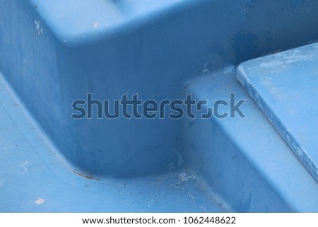 Detail of part of a boat polyester deck. Geometric shape painted in clear blue. Square element with round corners. Abstract image with lines and angles. Close up outdoor view of a graphic object. 