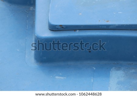 Detail of part of a boat polyester deck. Geometric shape painted in clear blue. Square element with round corners. Abstract image with lines and angles. Close up outdoor view of a graphic object. 