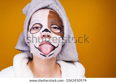 cute young girl with a towel on her head showing tongue, on face mask with muzzle of dog