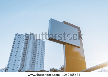 Mock-up of a blank horizontal white advertising billboard with residential high-rise behind; the template of an empty city advertising road banner with the block of flats in the background, evening