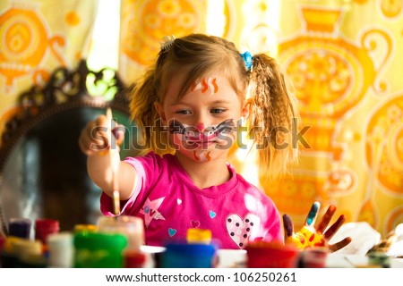 Little girl drawing paint with paint of face