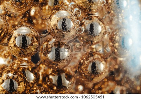 Gold beads in water with bubbles, macro, photo, background for design or Wallpaper. 