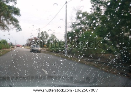 Blurred image, raindrop on the windshield, traffic in the city on a rainy day, car windshield view, colorful bokeh.