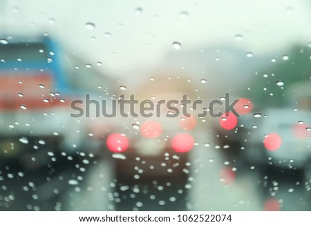 Blured background with rains drop on glass and cars on the road, There is a traffic jam in It's raining. There are a lot of car on the road. This picture was taken in Thailand. 