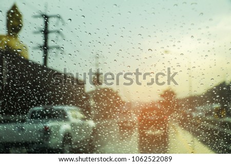 Blured background with rains drop on glass and cars on the road, There is a traffic jam in It's raining. There are a lot of car on the road. This picture was taken in Thailand. 