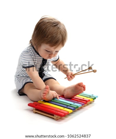 Beautiful baby 1.5 years studying xylophone. Isolated on a white background.