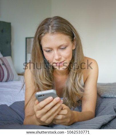 Young woman text messaging on mobile phone in bed