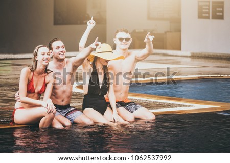Group of friends enjoying summer time in a swimming pool.