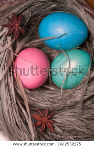 Colorful easter eggs in basket in the hay of the green grass straw bundle dietary delicious gift on wooden table. Top view with copy space