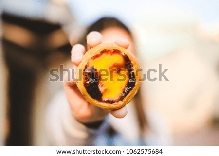 Hand of young woman holding fresh egg custard tart, soft to focus, food concept.