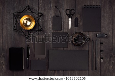 Modern stylish working place with blank black stationery on dark wood board. Template for branding, business presentations and portfolios.