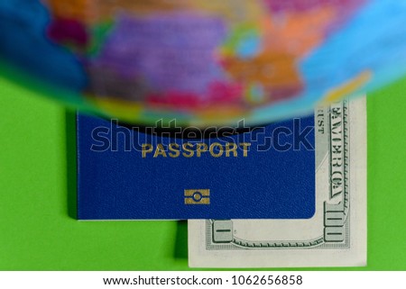 One hundred dollars and a passport on a green background with a map of the globe