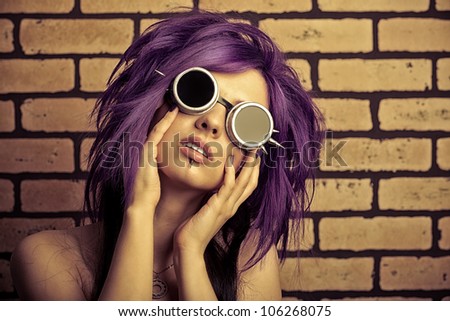 Portrait of a punk girl posing over brick wall.
