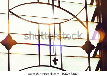 Silhouette of the cross hang over window with sunlight and bokeh effected, copy space, Christian background