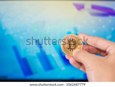 Close up man hand holding  bitcoin on a laptop with finance graph