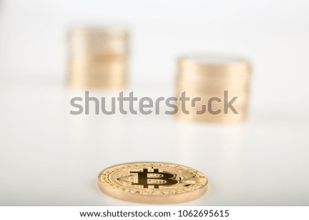 Stack of bitcoins with bitcoins background with a single coin facing the camera in sharp focus with shading on the icon letter B on the face of the bitcoin