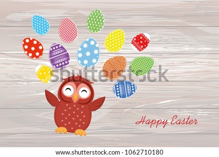 A cute owl has a happy smile and turns many colorful Easter eggs. Greeting card for the holiday. A blank space for your text or advertising. Vector on wooden background.