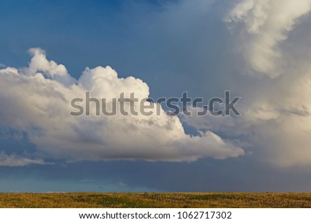Beautiful fluffy clouds of gray and white, in the form of an explosion, this is rarely found. Landscape with a majestic sky and a line of earth and horizon in the countryside
