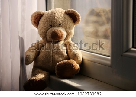 Cute teddy bear at home in white room is sitting near window. Royalty-Free Stock Photo #1062739982