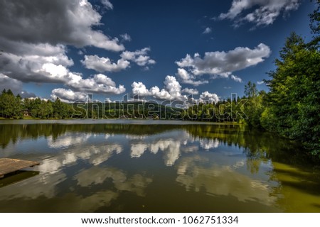 Beautiful lake Milovy with great reflection of trees and sky with clouds on water in Bohemian-Moravian Highlands, Czech Republic