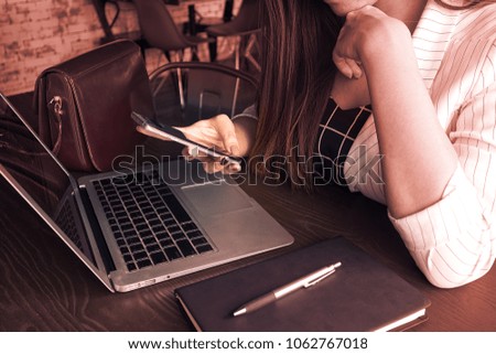 Business women use mobile phone sit on working table which have notebook and memo book and women's bag