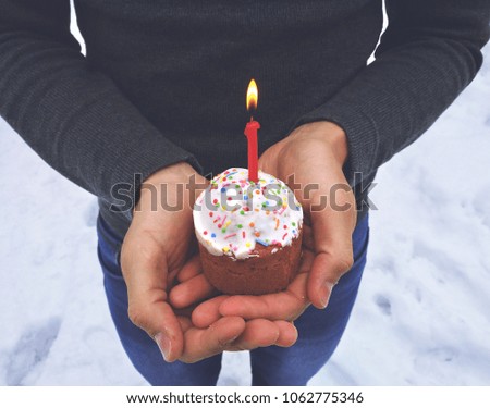 The man is holding a small Easter cake with a burning candle. Orthodox holiday.