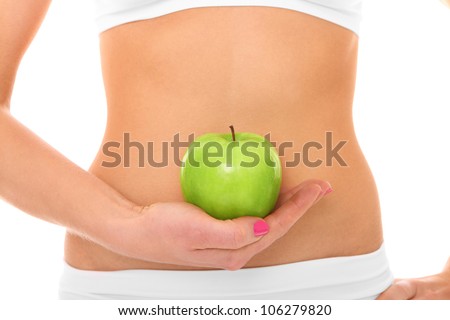 A picture of a woman holding a green apple in front of her fit belly