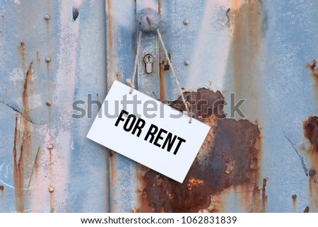An old, rusty door and a sign with the imprint For Rent
