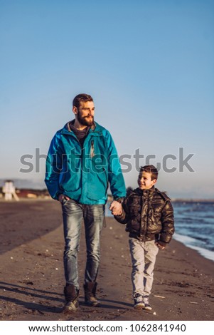 Father and son have fun on beach on sunny day