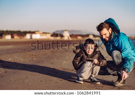 Father and son have fun on beach on sunny day