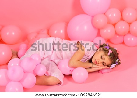 A portrait of a beautiful little girl sleep in the studio with many balloons pink color