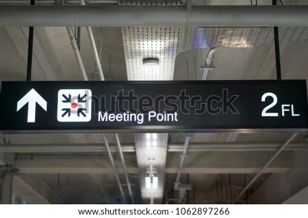 Meeting point information board sign with white character on black background at international airport terminal.