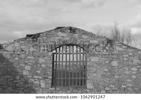 An iron grating of an ancient ruin made of bricks against sky. Black and white photo.