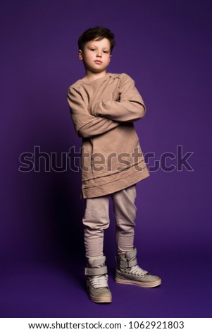 Be trendy and stylish! Full length picture of the serious little boy crossing arms on the chest and posing at the camera.