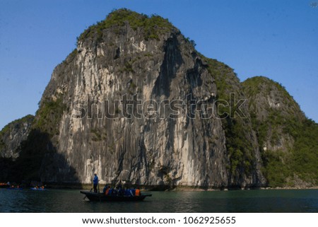 The rowing man take the tourist in bamboo boat to explore Halong Bay