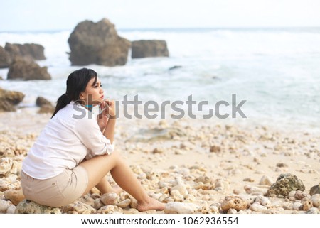 Beautiful Girl in sea style sitting on stone and sand. Travel and Vacation Freedom Concept. woman relaxes and enjoys the sea sitting on the beach.