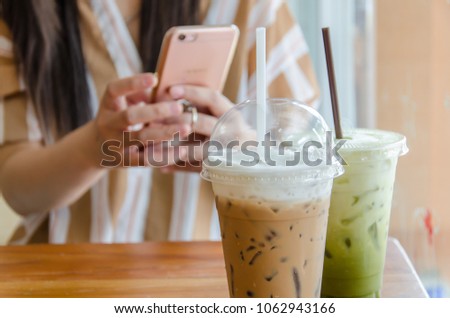 Ice green tea and mocca with  the hand that is going to take a picture In Plastic cup in coffe shop