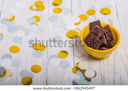 Chocolate in yellow bowl with confetti on wood