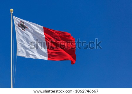 Malta flag. Malta flag on a flagpole waving on a bright blue sky background Royalty-Free Stock Photo #1062946667