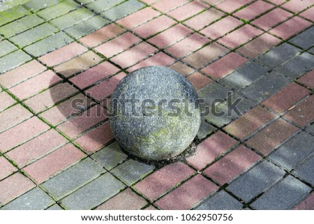 A large ball of gray stone on the pedestrian sidewalk