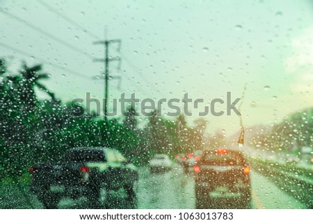 Blurred background with rains drop on glass and cars on the road, There is a traffic jam it's raining. There are a lot of car on the road. This picture was taken in Thailand.