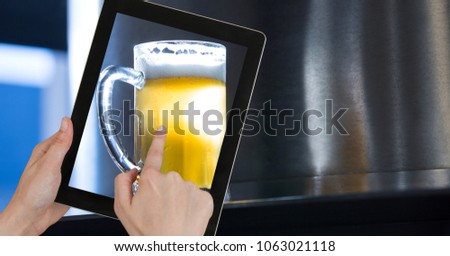 Hand taking picture of beer glass through digital tablet