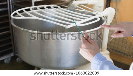 Hand taking picture of utensil with transparent device at bakery
