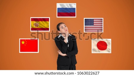 Thoughtful businesswoman standing by flags against orange background