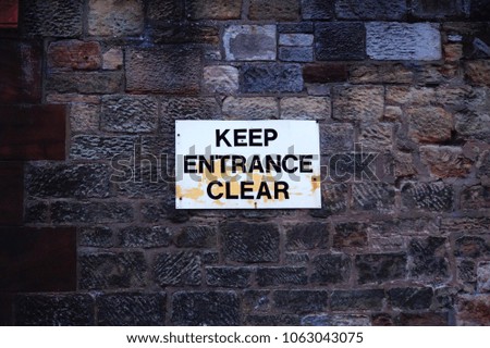 Keep Entrance Clear worn out sign on brick wall