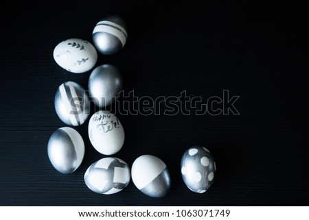 Group of diverse silver Easter eggs on black background, original stylish idea, selective focus