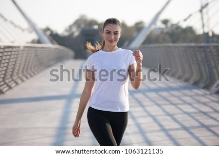Sports woman in a white T-shirt while training on the bridge. Mock-up. Royalty-Free Stock Photo #1063121135