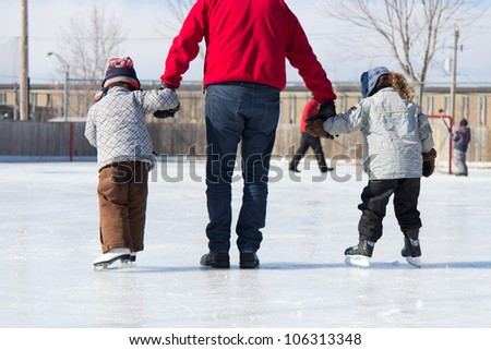Family having fun at the outdoor skating rink in winter.