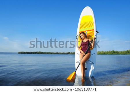 Wide picture of a woman with sup board on river background